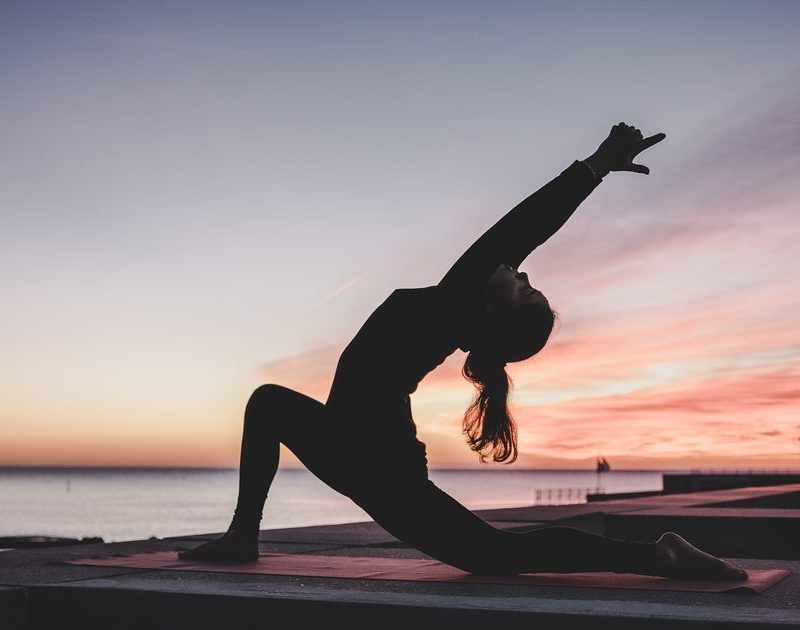 Silhouette of a woman practicing yoga at sunset